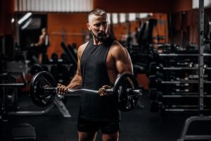 Homme qui s'entraîne au biceps curls à l’intérieur d’un gym.