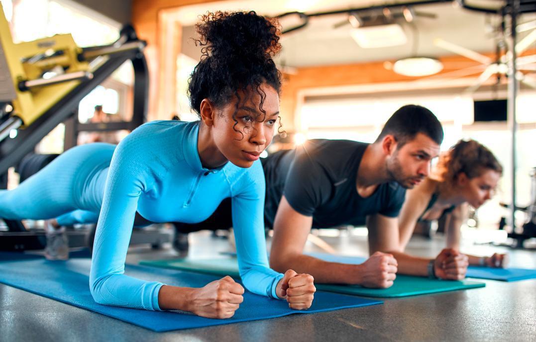 Cours collectif pour hommes et femmes en exercice de planche abdominale. 